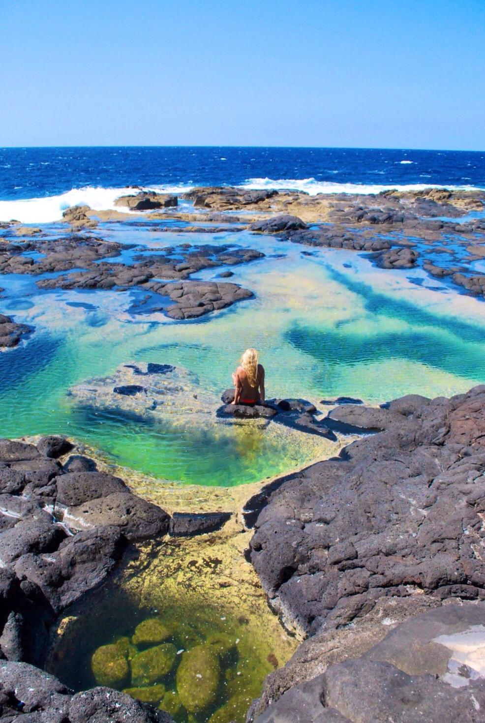 woman with blonde hair sat relaxing in the natural pools of Los Charcones